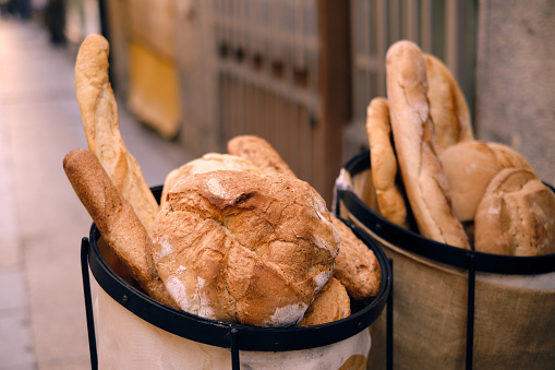 Freshly baked traditional breads in a basket on a street. Delicatessen Bakery image.