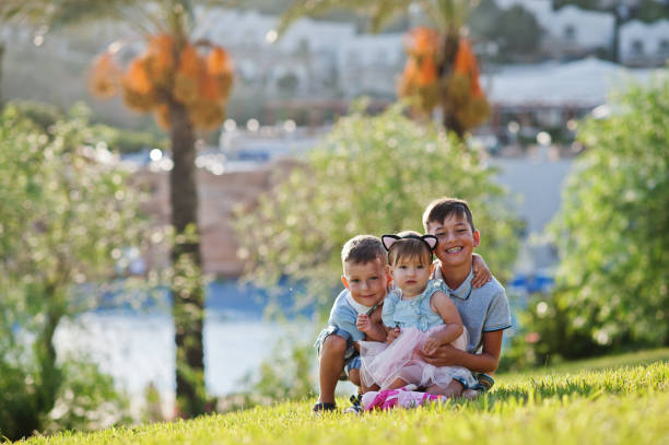 Portrait of kids. Three little smiling girls lying on grass. Looking at camera.