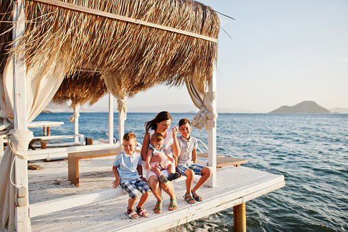 Mother with three kids on Turkey resort sitting bungalow against Mediterranean sea.