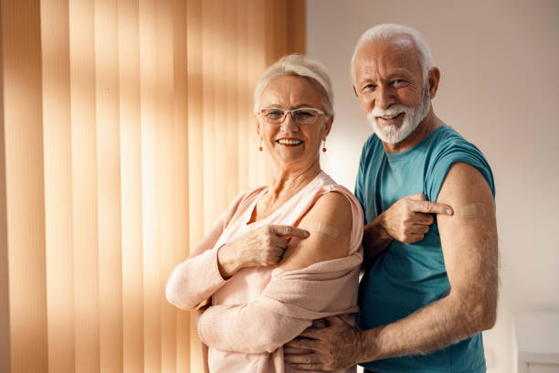Viral vaccination and immunization during covid 19. A happy senior couple showing their arms after covid 19 vaccine with adhesive plasters. stock photo