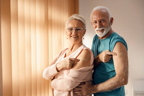 vacinação viral e imunização durante o covid 19. um casal de idosos feliz mostrando seus braços após a vacina covid 19 com plasters adesivos. - caderneta de vacinação - fotografias e filmes do acervo