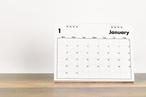 January 2022. White desk calendar on wooden table.