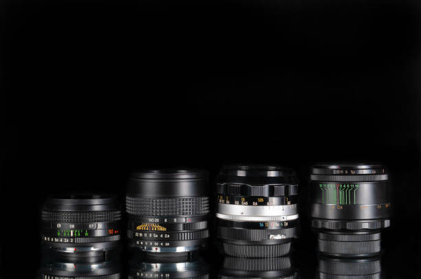 istock Modern and old DSLR camera lens set on black background with reflection 1358966725