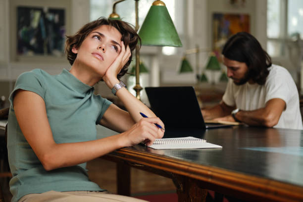 istock Young thoughtful female student with notepad dreaming during study in library of university 1358966789