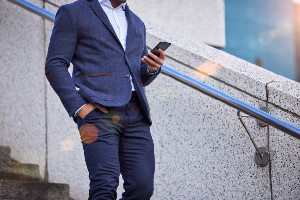 istock Shot of a businessman using his smartphone while walking down stairs 1358967752