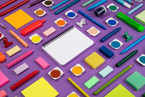 Back to school concept with crayons and school supplies on purple background