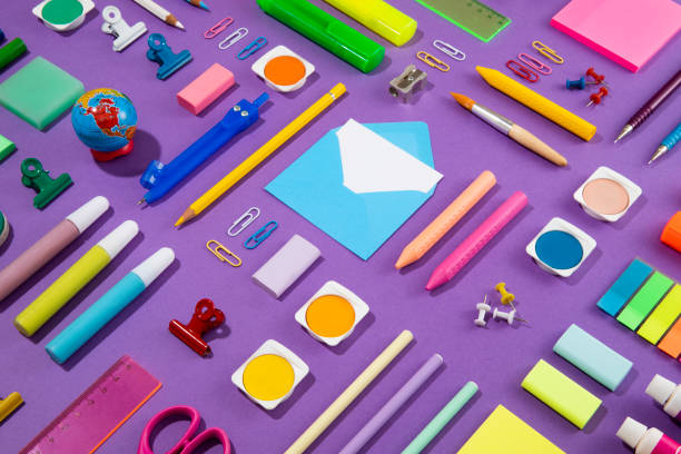 Back to school concept with crayons and school supplies on purple background