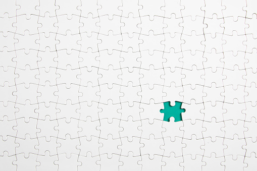 White puzzle pieces background with one missing piece left