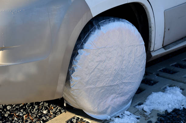 caravana garantida por uma longa vaga de estacionamento. a roda do carro e a borracha estão cobertas com uma tampa de plástico. sal d'água e neve não pegam os freios. discos não enferrujam. - tire car brake rain - fotografias e filmes do acervo