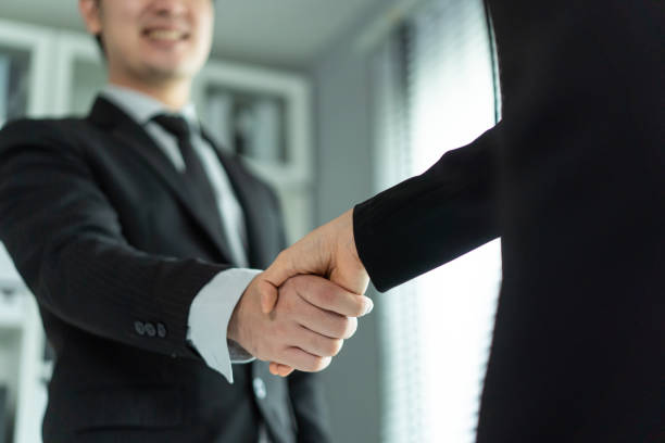 Asian woman handshake with hr manager after job interview in office. Attractive beautiful female employee shake hands with human resources manager businessman after apply recruit and hire at workplace stock photo