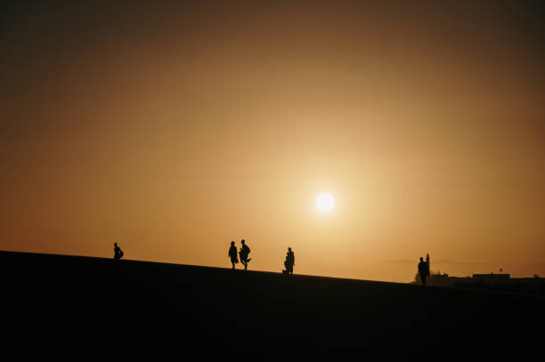 istock Silhouette of people walking on a dune 1358975148
