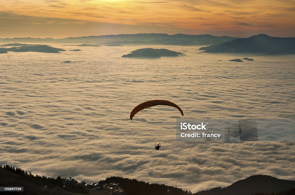 Paraglider in the sunset A paraglider is gliding from the hill into the foggy sunset. BASE Jumping Stock Photo