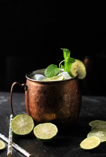 istock Icy Cold Moscow Mule Coctail on Copper Mug  with Ginger Beer, Lime,  and Vodka, Garnish with Mint Leaf. Isolated on  Black Slate Background 1358977674