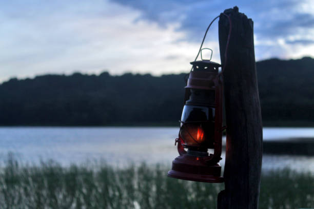 istock Old classic oil lantern on the blue lake background. 1358978061
