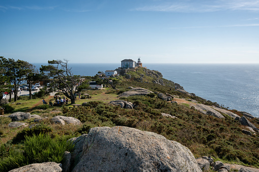 Finisterre, Spain - October 3, 2019 : Cape finisterre landmark lighthouse with tourists on a sunny day in Galicia, Spain