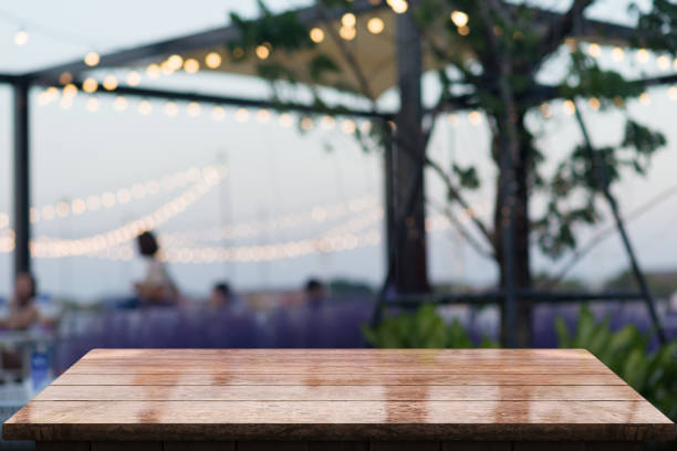 Empty wooden tabletop with lights bokeh on blur restaurant background.