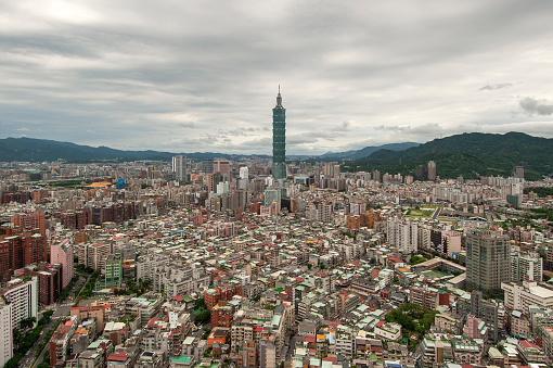 An elevated view of Taipei City with Building No 1  and wooded hills on the horizon.