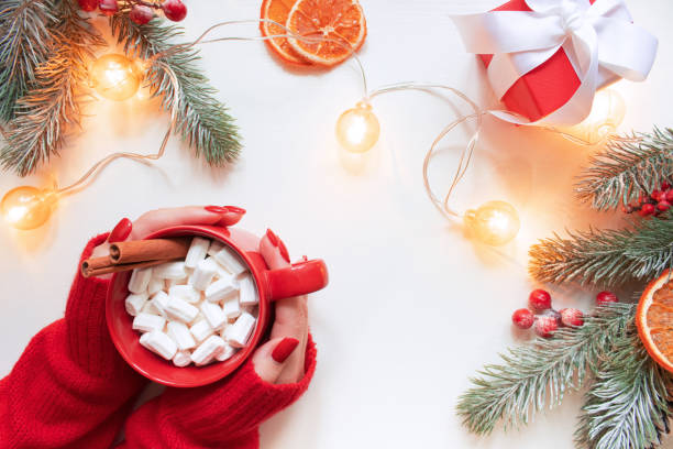 istock Female hands with red cup hot chocolate on the white background. Christmas composition. Top view. Copy space 1358981775