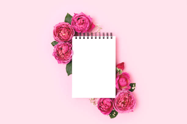istock Border frame made of rose flower and notepad mockup on a pink pastel background. 1358982584