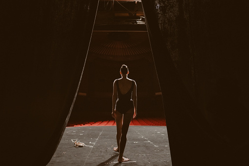 Photo of a ballerina rehearsing alone on the stage of a theater.