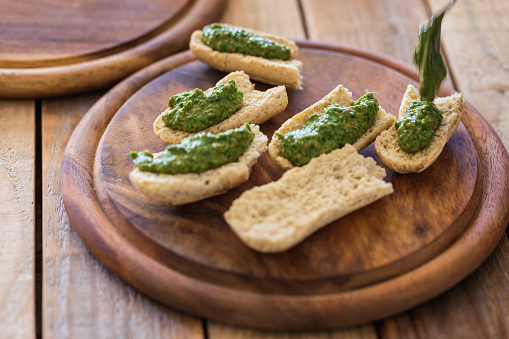 Green pesto made from raw ramson leaves, olive oil, garlic and crushed dry fried almond seeds on piece of bread