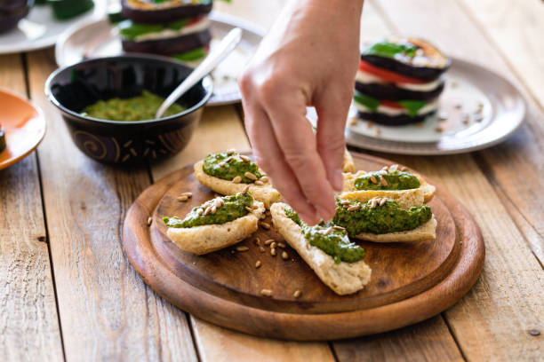 Green pesto made from raw ramson leaves, olive oil, garlic and crushed dry fried almond seeds on baguette pieces,  hand sprinkles dry fried sunflower seed