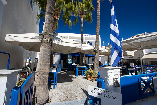 Pavement Cafe in Firá on Santorini in South Aegean Islands, Greece, with people and advertised tours in the background