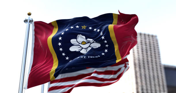 la bandera del estado estadounidense de mississippi ondeando en el viento con la bandera estadounidense borrosa en el fondo - mississippi fotografías e imágenes de stock