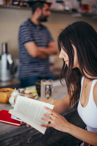 istock Woman reading book at coffee shop 1358986702