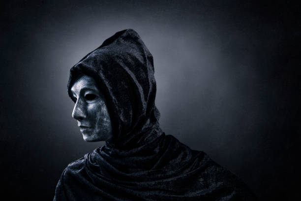 istock Scary figure with hooded cloak in the dark 1358988092