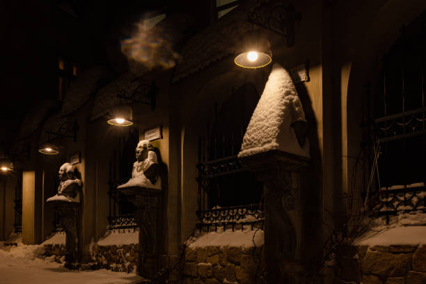 Bastion of Vilnius medieval defensive wall in Vilnius Old Town, evening or night view with old buildings and street lamp in winter with snow, black and white