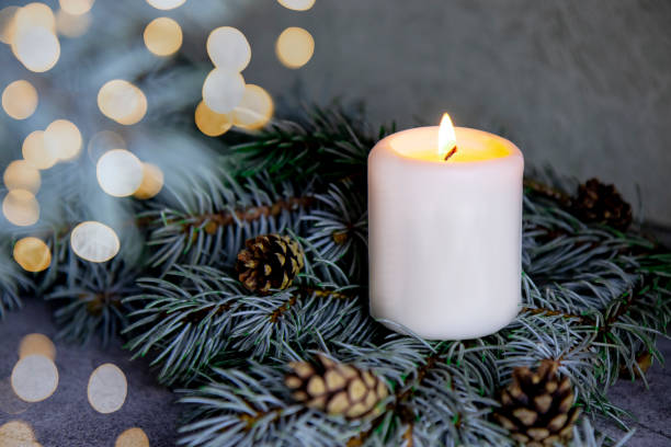 istock selective focus on beautiful lighted candle standing on green christmas tree, new year holidays concept, home decor, DIY home decoration 1358988119