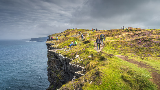 Doolin, Ireland, August 2019 Group of people or tourists hiking and sightseeing iconic Cliffs of Moher, popular tourist attraction, Wild Atlantic Way, County Clare