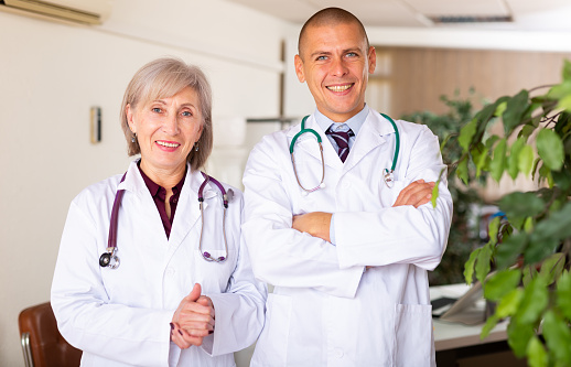 Portrait of two smiling confident professional doctors standing in medical office