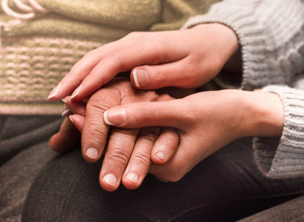 two people hold hands - holding hands human hand senior adult consoling imagens e fotografias de stock