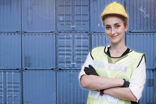 istock workers woman engineering standing with confident with blue working suite dress and safety helmet. manual worker in front container background. Concept of smart industry worker operating. 1358993586