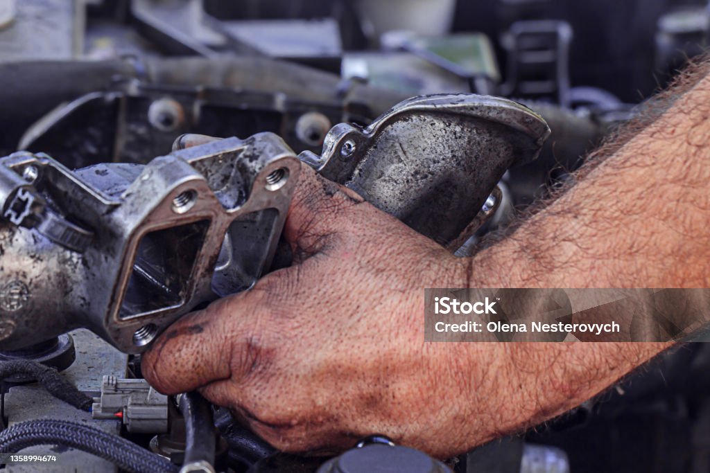 Dirty, greasy hands of a man repairing the engine, EGR valve in the car close up. Car Stock Photo