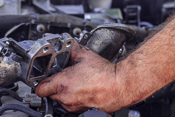 Dirty, greasy hands of a man repairing the engine, EGR valve in the car close up. stock photo