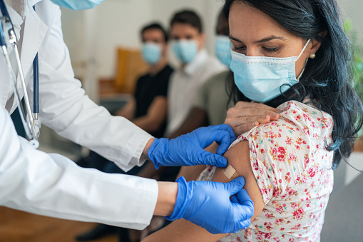 Doctor putting plaster after Injecting COVID-19 vaccine into patient's arm in vaccination center