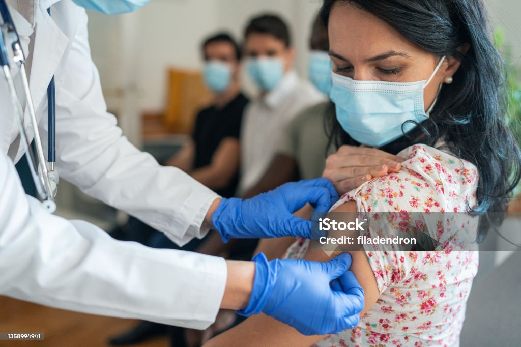 Vaccination center Doctor putting plaster after Injecting COVID-19 vaccine into patient's arm in vaccination center Booster Dose Stock Photo