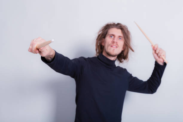 istock Rock and roll music concept. Funny dreadlocks men holds drumsticks in hands on a gray background free space for text. Education, teacher, online lessons concept 1358995051