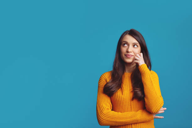 Thoughtful cute girl considers something keeps hand on looking at empty free space Thoughtful pretty teenage girl considers something keeps hand on looking at empty free space, isolated over white background with copy space suspicious message stock pictures, royalty-free photos & images
