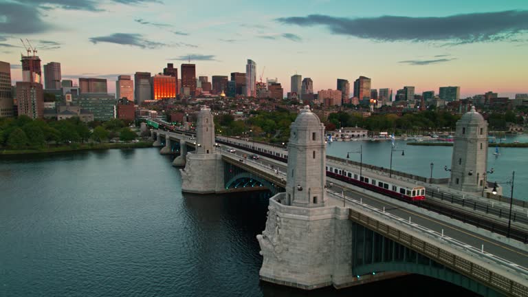 Aerial establishing shot of Boston, Massachusetts at sunset, looking across the Charles River towards the downtown skyline and following a red line train.
Authorization was obtained from the FAA for this operation in restricted airspace.