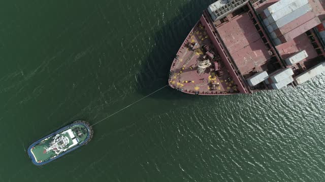 Towing operation. Steering a container ship A tug pulls a container ship by the bow for entry and exit to the seaport.