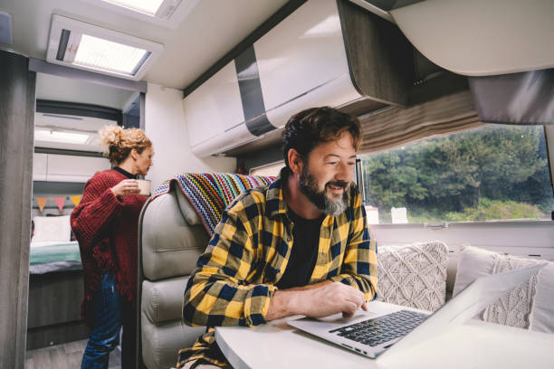 istock Alternative nomad lifestyle office workstation people. Man working on laptop computer inside luxury van during vacation or alternative digital lifestyle. People working online everywhere 1359005459