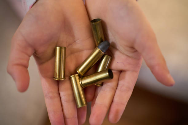 istock Open hands holding several unexpired revolver bullets and several bullet casings already struck 1359006007
