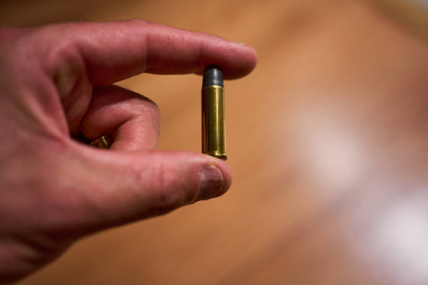 Hand holding a revolver bullet with two fingers without having been fired. High quality photo