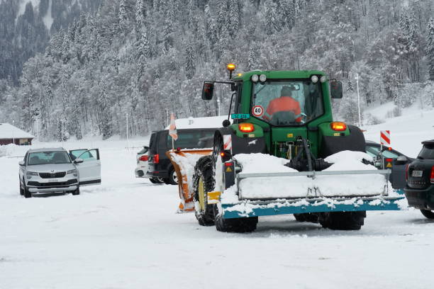 heavy tractor with rear dozer blade in parking lot with cars in cross country skiing resort in switzerland. - snowplow snow parking lot pick up truck imagens e fotografias de stock