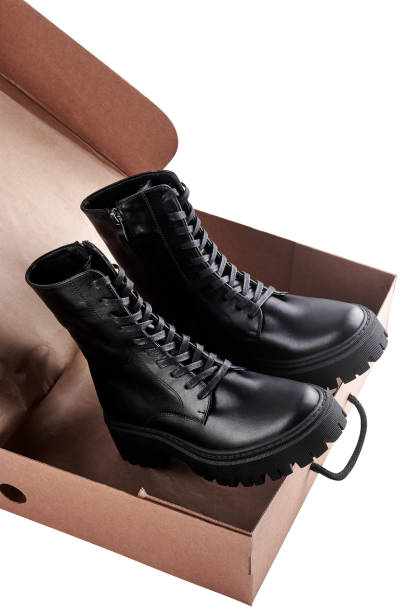 istock Black leather female boots in paper box isolated on white background, copy space. Delivery concept 1359011636