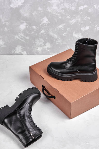 istock Black leather female boots in paper box isolated on white background, copy space. Delivery concept 1359011648